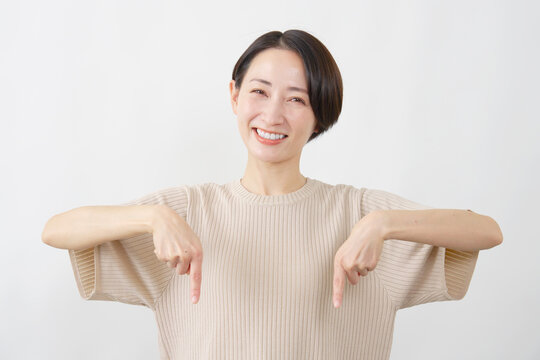 両手で下を指差す笑顔の女性　白背景