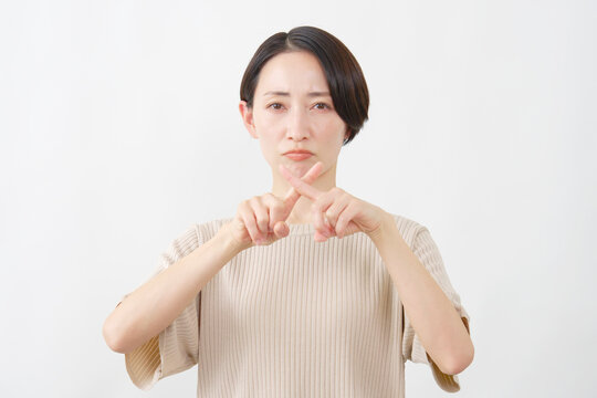 指でバツをつくる女性　ミドルエイジ　白背景