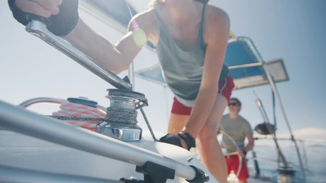 Couple sailing the small sailing boat in the calm sea during nice sunny day, man steers and woman works with the ropes