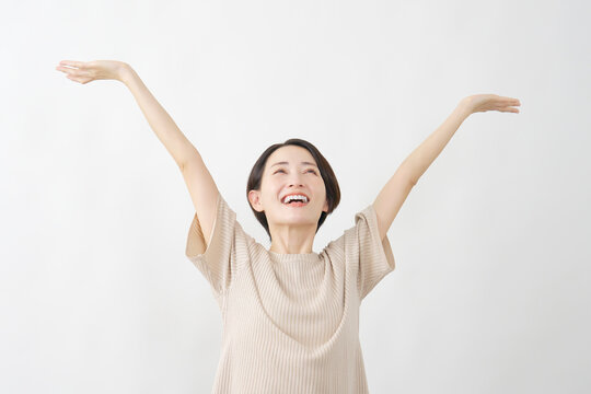 両腕を広げて伸びをする女性　白背景