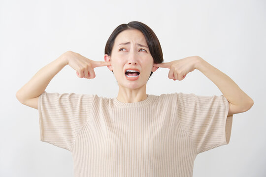 うるさくて耳を塞ぐ女性　白背景