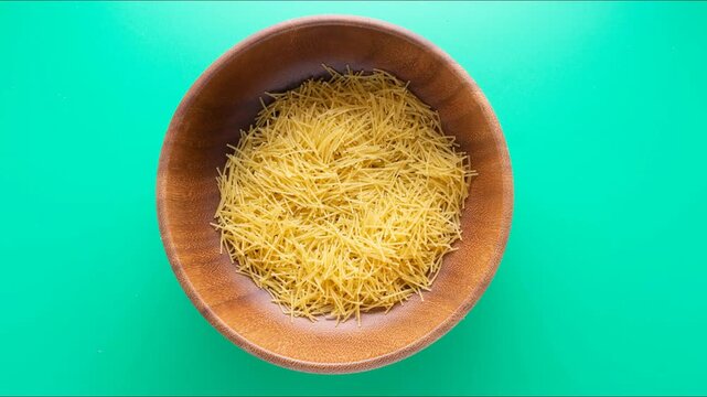 Stopmotion: eating dry pasta from wooden bowl. Top view, close  up