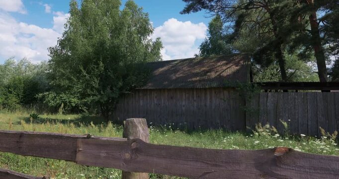 Old wooden barn behind a rustic fence in the countryside
