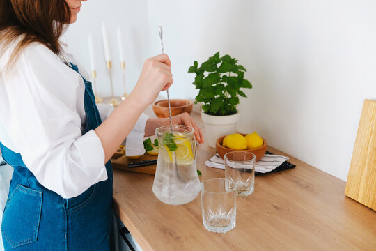 woman preparing fresh lemonade with mint and lemons