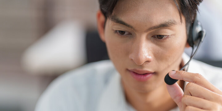 Close up of Asian male call center operator wearing headset