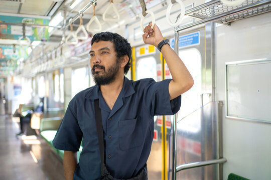 Indonesian Passenger Standing Inside KRL Train Holding Hand Strap