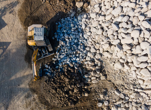 Aerial Scenery of Excavator Operating in Rock Quarry Mine with Gravel and Boulder Extraction, Construction and mining site view from above 