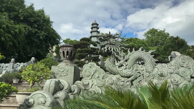 Da nang, lady buddha, stone dragon sculpture with traditional cloud patterns, guarding a pagoda and lush gardens under a cloudy sky in da nang, vietnam