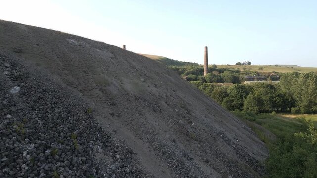 4K Drone Ascent Beside Slag Heap Revealing Historic Waterside Ironworks