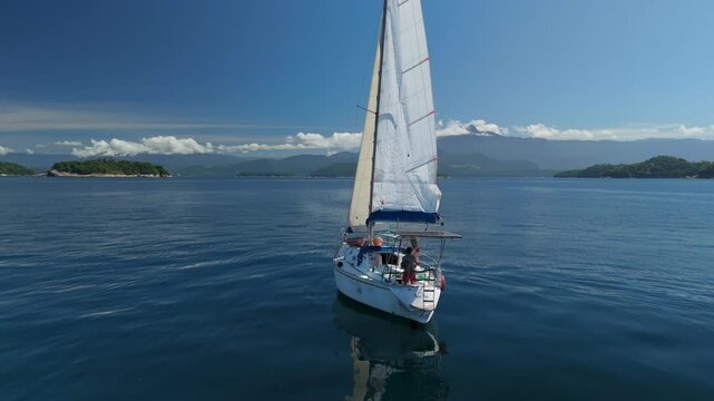Speed warp sailing. Sailing boat moves in the tropical sea near the Brazilian shore during nice sunny day. Aerial drone shot of the sailing boat with speed ramp effect, drone orbits the boat