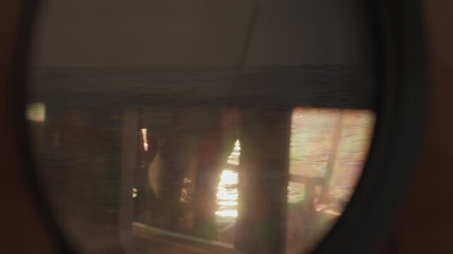 Expeditional sailing vessel moves in the open ocean, view through the window with water reflection