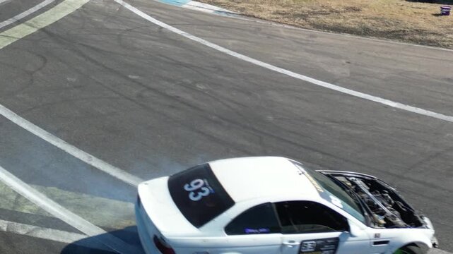 Modified drift car without hood performing controlled drift on a dedicated motorsport track. Exposed engine, high-speed cornering and professional drifting captured in dynamic automotive footage.