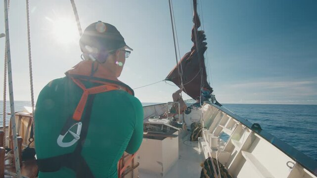Crew work with the sails on the big expeditional sailing vessel moving in the Atlantic Ocean