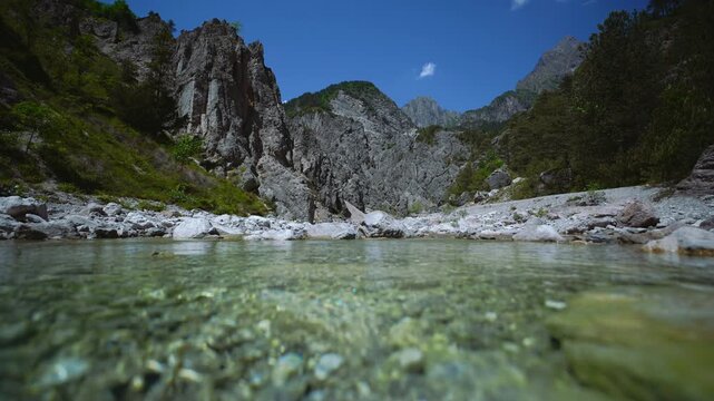 Cinemagraph seamless loop of clear mountain stream water flowing over pebbles, Dolomites, Italy.