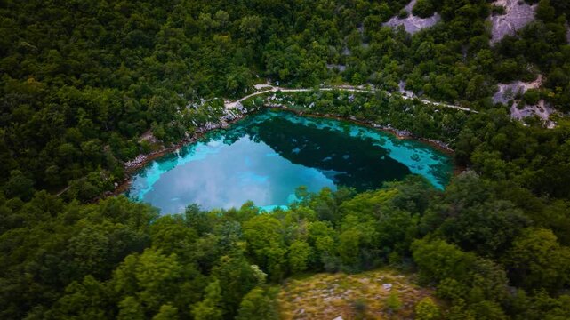 Clear alpine lake Lago Cornino with clear blue water surrounded by dense green vegetation in Northern Italy.
