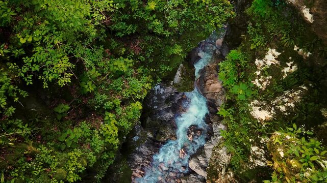 Clear mountain river flowing through steep limestone cliffs in Cellina gorge, Sentiero del Dint, Italy.