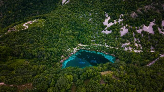 Crystal clear alpine lake Lago Cornino surrounded by lush green trees, Italy. Blue water aerial drone