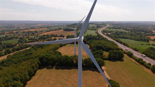 Extreme close aerial flyby captures massive wind turbine blades sweeping through open sky.