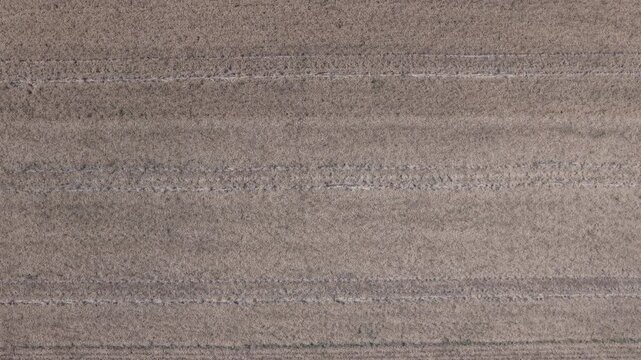 An abstract aerial perspective captures a cultivated agricultural field, showcasing intricate linear patterns and natural texture of the earth.