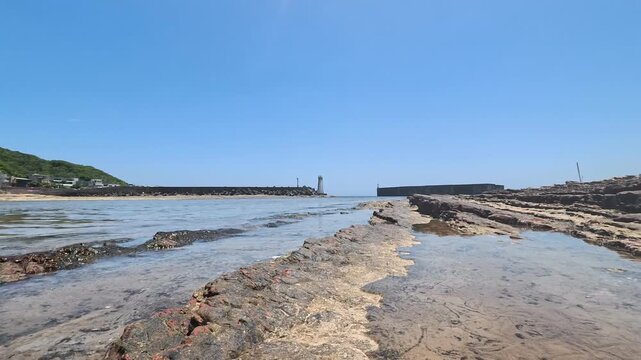 Wide Perspective Of Rocky Coastal Terrace Platform Leading Toward Harbor Entrance Under Sky, 4K b-roll