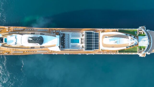 High-angle aerial top-down drone footage of the luxury cruise ship Viking Vesta navigating the crystal-clear turquoise waters of Corfu Island, Greece. The shot captures the elegant symmetry of the upp