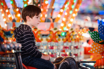Thoughtful young boy on elephant carousel ride with colorful bokeh lights © Oleksii Yemelianov