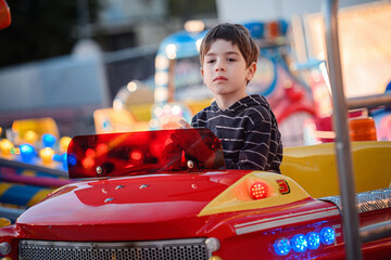 Detailed low angle portrait of boy in high flying red carousel car © Oleksii Yemelianov