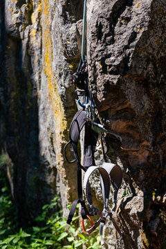 Rock climbing harness and gear hanging on cliff with rope