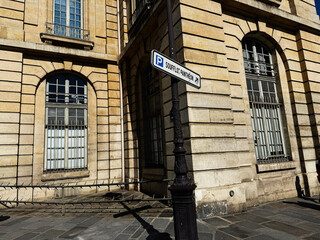 Obraz premium Historic Paris France street corner with sandstone building, arched windows and Soufflot Panthéon parking sign in warm sunlight