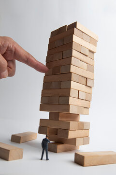 Precarious wooden blocks and miniature businessman