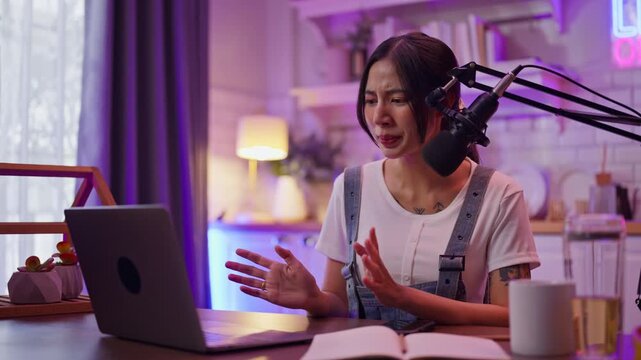 Smiling young asian woman recording podcast from her home studio.Joyful woman recording live podcast.Vlogger live streaming podcast review on social media,Asian woman use microphones wear headphones
