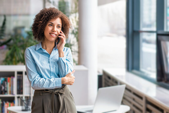 Smiling black businesswoman talking on smartphone standing
