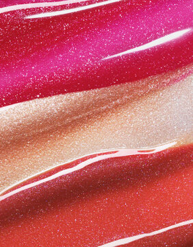 Pink red and gold shimmering lip gloss texture background. Smudged cosmetic product smear. Makup swatch product sample