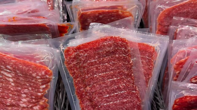 Packaged sliced salami and cured meats in plastic wrap displayed on a store shelf