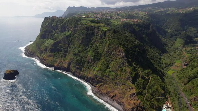 Sao Jorge Madeira island Portugal 4K. Aerial drone high altitude backward flyover reveal of wild coast and winding mountain road to ocean pools in gorge. Remote nature travel b roll stock video