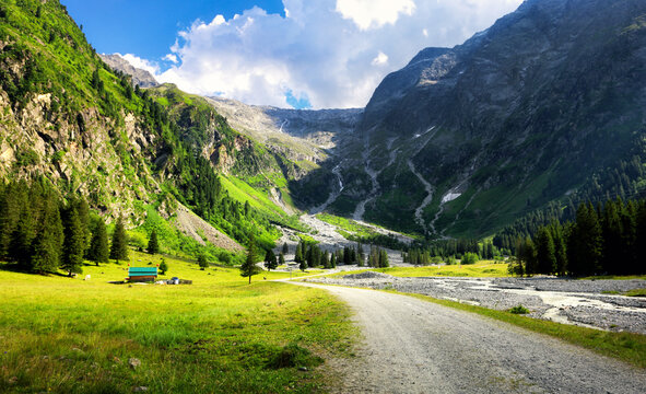 Austrian Alps with snow-capped peaks, lush green valleys, and a small mountain village under a clear blue sky - Lusenstal near Innsbruck