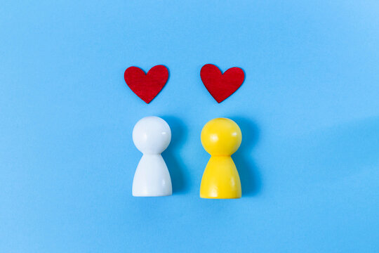 Diverse couple symbolized by colored wooden figures with red hearts