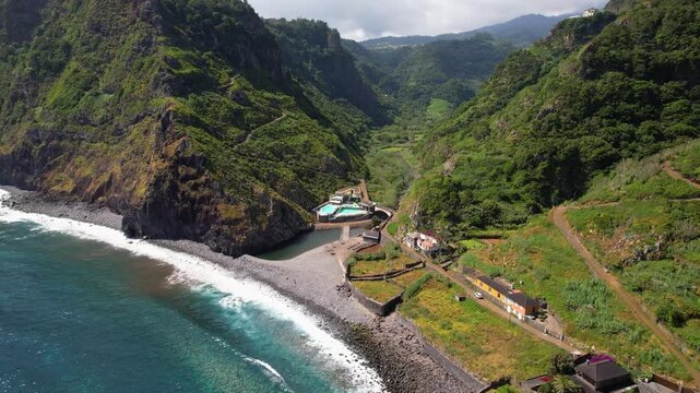 Sao Jorge bathing complex Madeira Portugal 4K. Aerial drone approach turn reveal of rocky beach with filled ocean pools in mountain gorge no people. Remote coastal travel nature b roll stock video