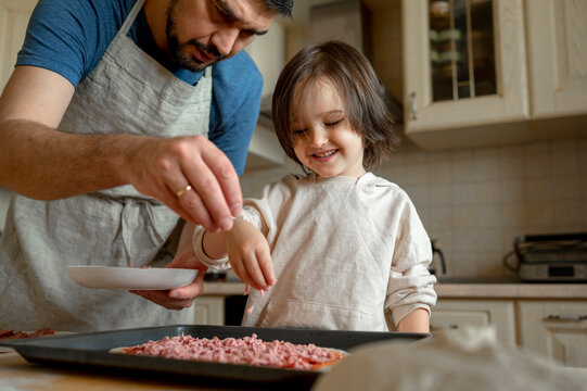 Father with son making pizza in kitchen at home
