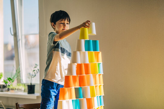 Child building a colorful paper cup tower at home