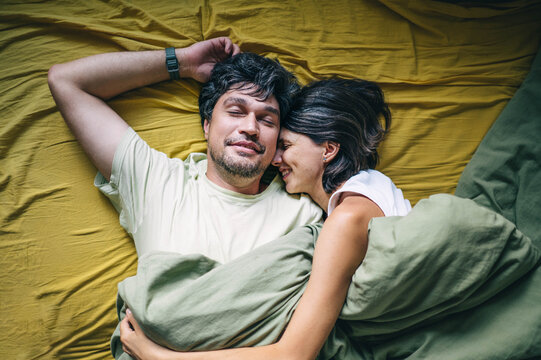 Smiling husband and wife hug each other in bed
