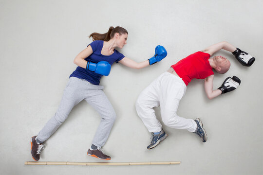 A woman punches a man during a playful boxing fight in a studio