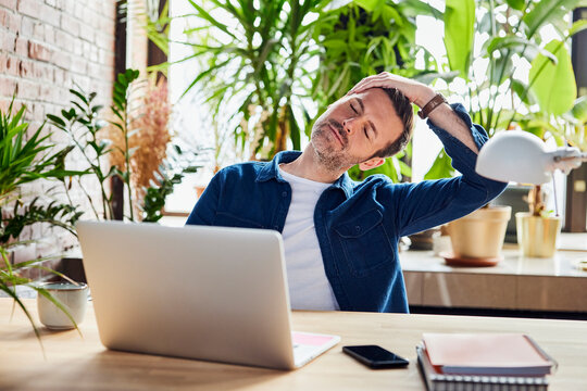 Businessman stretching neck after work at loft office