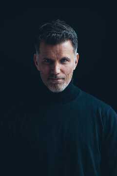 Portrait of man wearing black turtleneck in front of black background