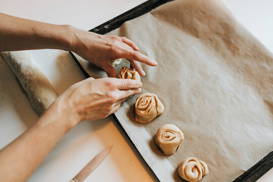 Woman arranging cinnamon rolls on baking sheet