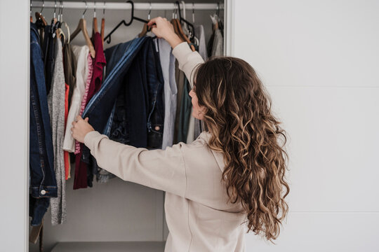 Woman selecting clothes from closet at home