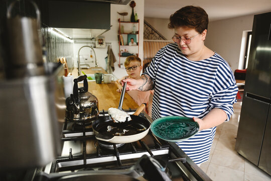 Woman making omelet with son standing by kitchen counter at home