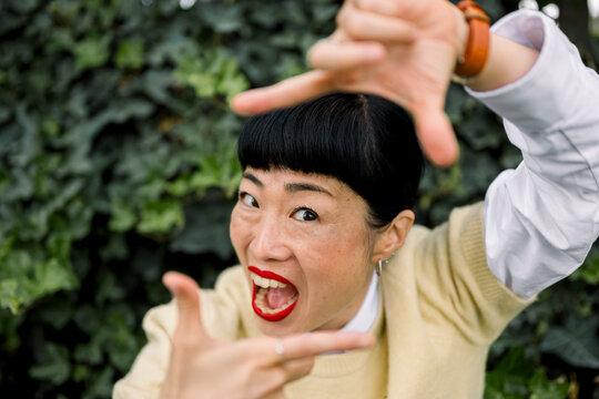 Expressive portrait of smiling woman making a playful gesture outdoors