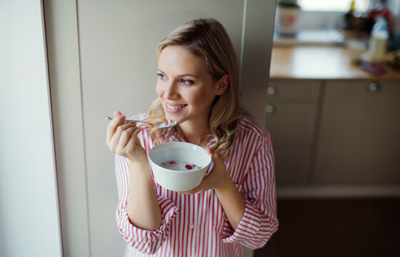 Smiling woman having breakfast in the morning at home