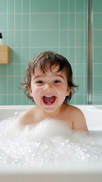 Delighted cute little boy taking a warm bubble bath at home smiling happily with fluffy white soap foam, showing joyful facial expression during evening hygiene routine time.